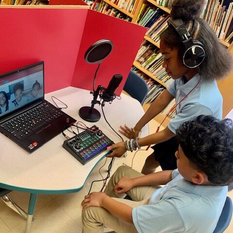 Two elementary students working with podcast equipment